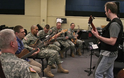 Army bassists in uniform playing together in a rehearsal room