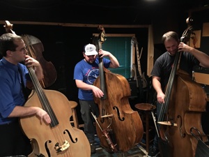 Three double bassists playing together in the studio