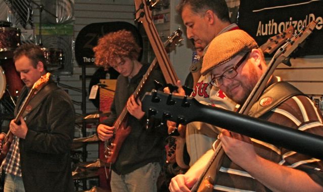 Students playing electric basses together in a music store classroom