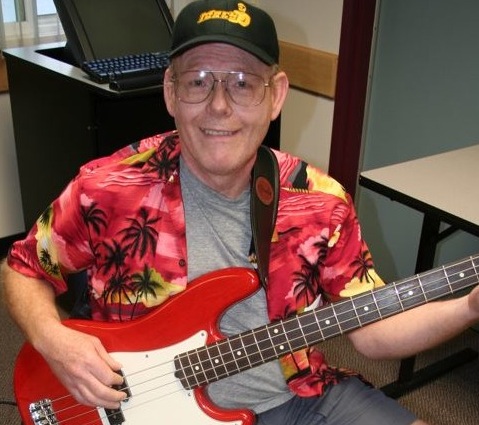 A smiling student in a Hawaiian shirt with a red bass