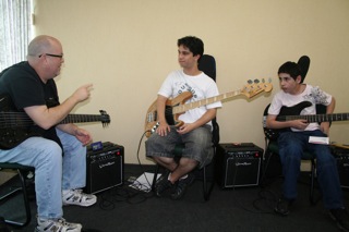 An instructor coaching two young bassists