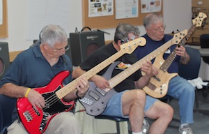 Three students playing electric basses side by side